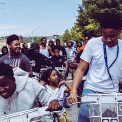 Group of black children riding bikes down a street