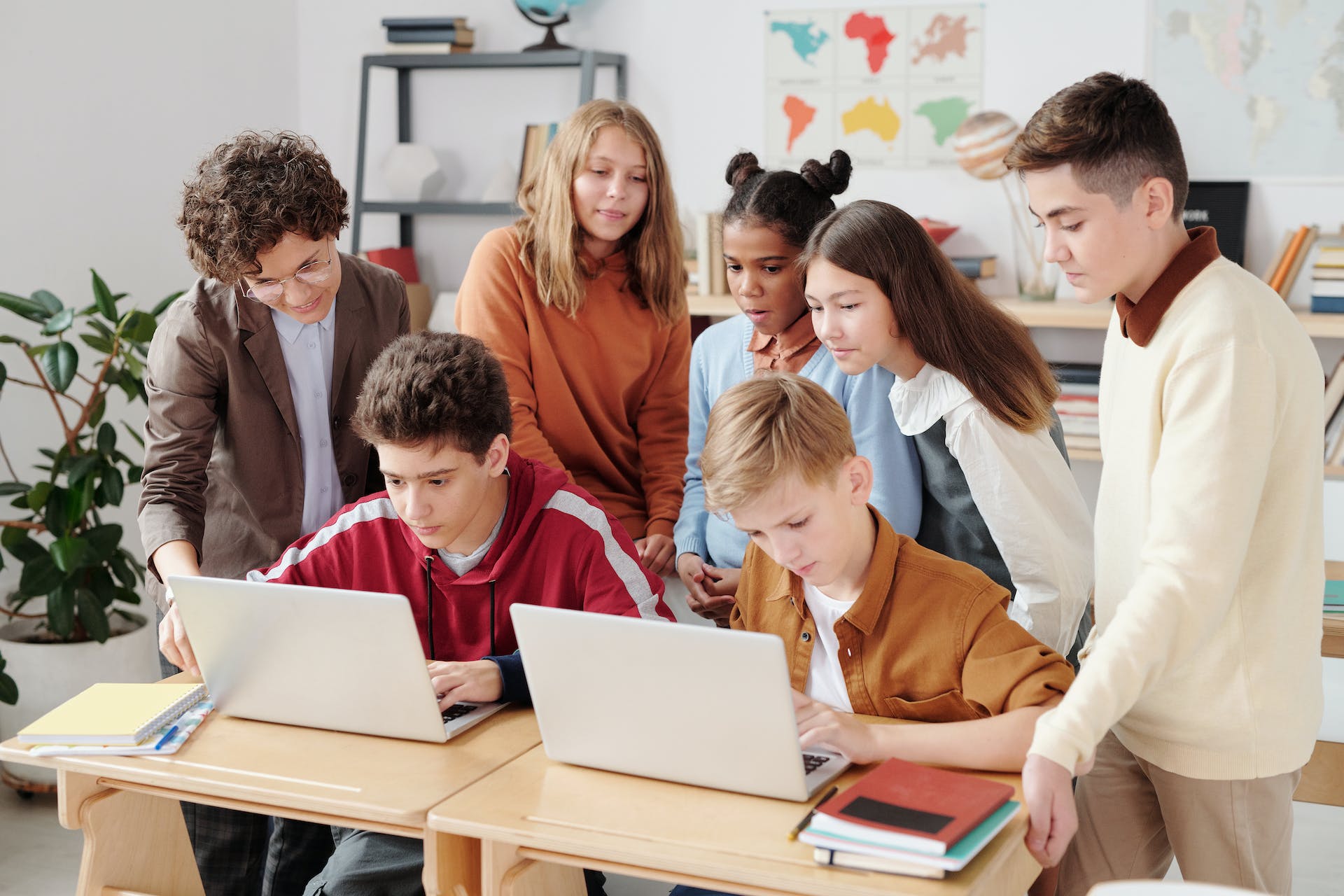 A group of middle school students gathering around a laptop